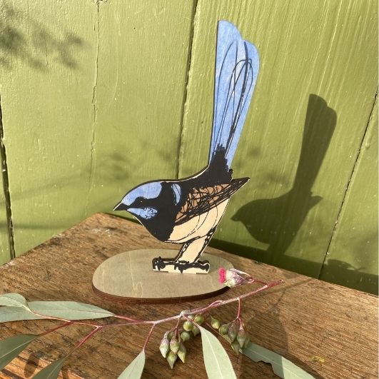 Decorative bird figure on a wooden surface with a green background