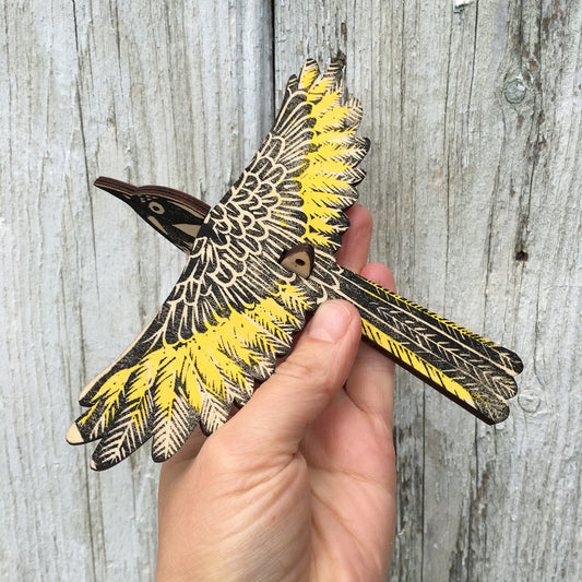 A hand holds a hand printed new holland honeyeater mobile 