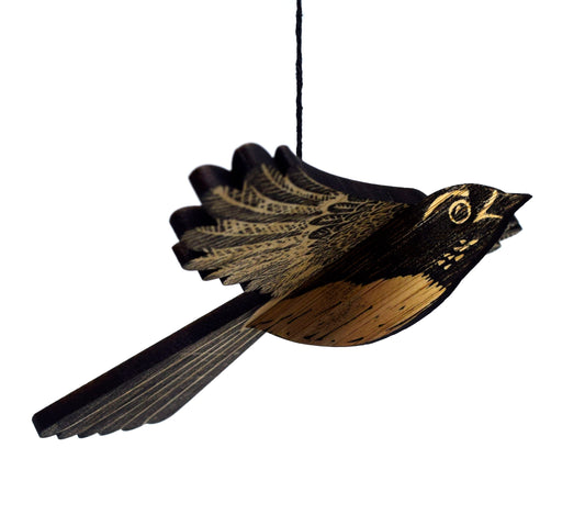 A handcrafted mobile depicting a willie wagtail bird, made from layered plywood with black and brown coloring.